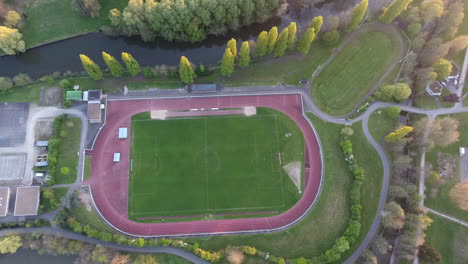 Football-field-with-a-running-track-around-view-by-drone-aerial-shot-sunset-time